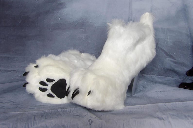 Puede incluir: Pies de disfraz con forma de pata, de piel sint&eacute;tica blanca, con almohadillas y garras negras. La piel sint&eacute;tica es larga y esponjosa, y las patas est&aacute;n dise&ntilde;adas para parecerse a las patas de un animal. Los pies de disfraz son probablemente para cosplay o una mascota.