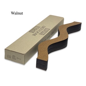 May include: A set of wooden slats in a walnut finish, arranged in a wavy pattern. The slats are packaged in a brown cardboard box with the text "ARTWOOD" and "Enjoy your slats" printed on it.