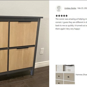 May include: A gray shoe cabinet with four doors. The doors have a vertical, ribbed design in a light wood color. The cabinet has a dark gray frame and black handles. Two small potted plants sit on top.
