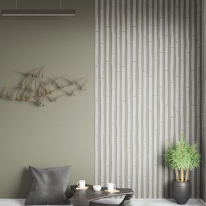 May include: A modern living room with a green wall and a bamboo-patterned wall. A wooden coffee table with two cups and a small bowl of snacks sits in front of a gray pillow. A potted plant sits on the floor next to the wall.