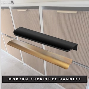 Könnte beinhalten: Zwei moderne Möbelgriffe, einer schwarz und einer goldfarben, montiert an einem hellen Holzschrank. Der schwarze Griff befindet sich über dem goldenen Griff. Der Text "MODERN FURNITURE HANDLES" befindet sich am unteren Rand des Bildes.