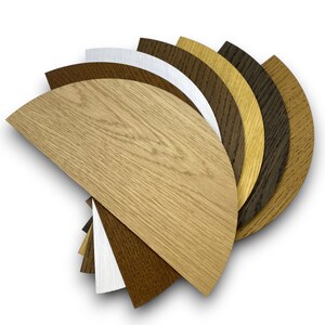 May include: A set of eight wood veneer samples in various shades of brown, from light to dark, arranged in a fan shape. The samples are in the shape of half circles.
