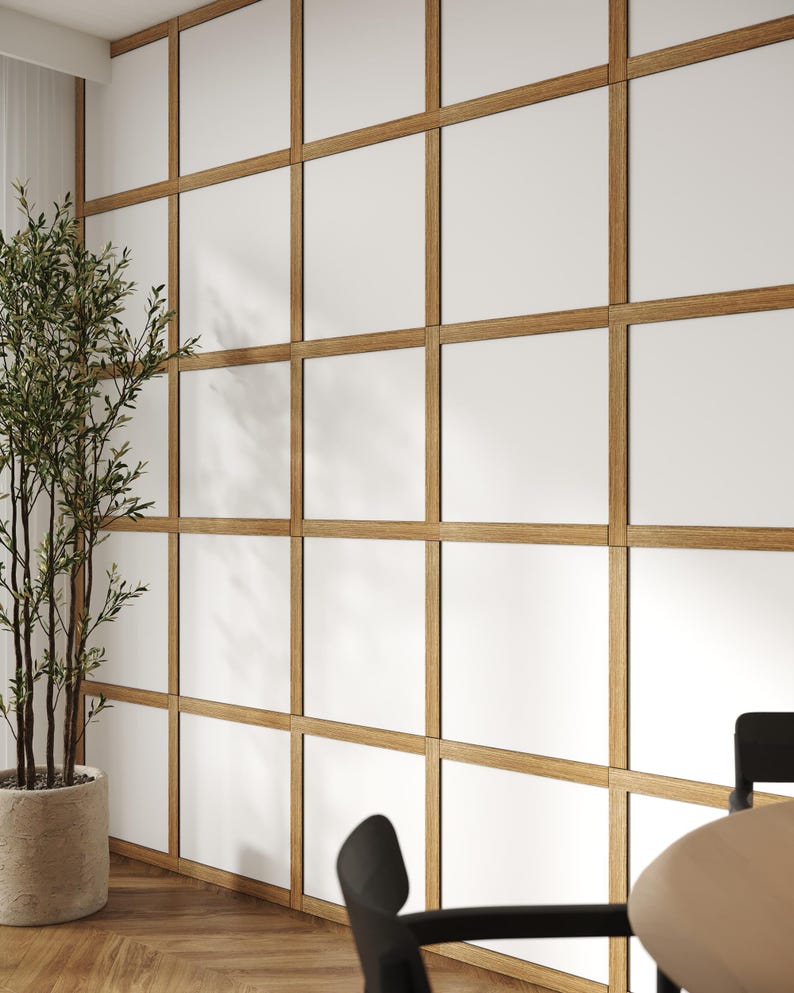 May include: A white wall with a wood paneling design. The panels are arranged in a grid pattern, creating a modern and minimalist aesthetic. The wall is illuminated by natural light, casting shadows on the panels.