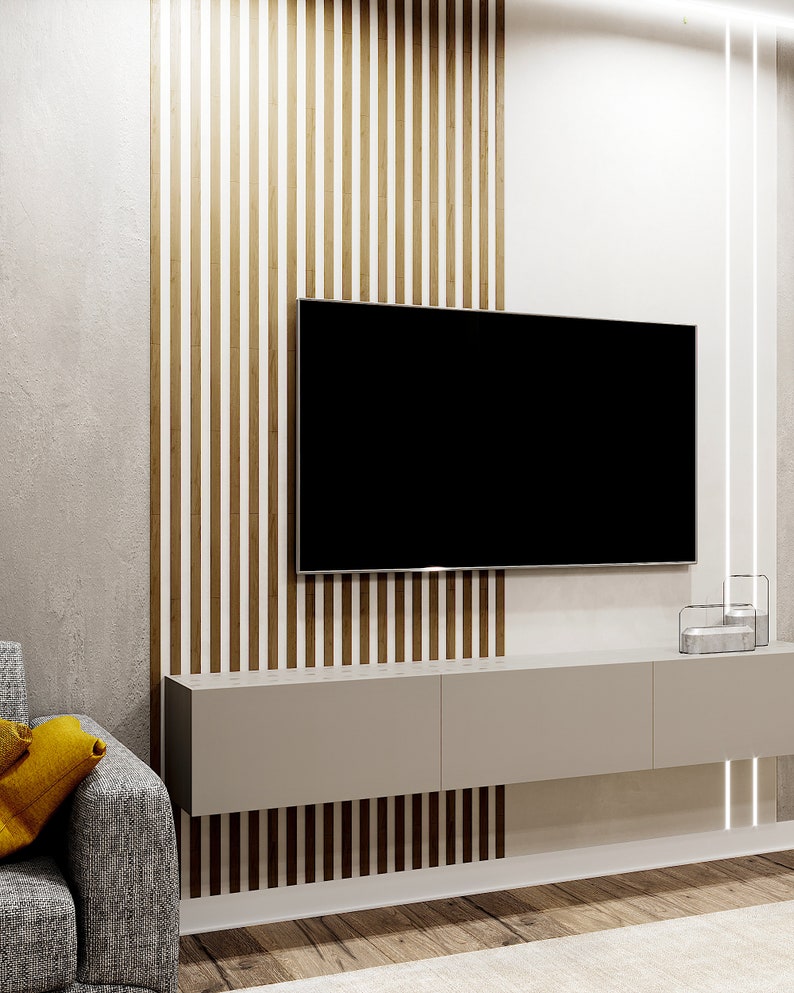 May include: A modern living room with a flat screen TV mounted on a wall with wood paneling. A gray floating shelf is below the TV with a decorative object on the right side. A gray couch with a yellow throw pillow is in the foreground.