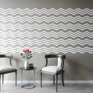 May include: Two black chairs with white cushions and a small round glass table with a vase of red roses. The wall behind the furniture is decorated with a white wave pattern.