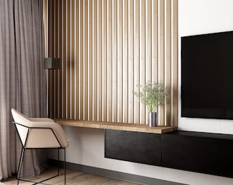 May include: A modern living room with a wooden slat wall, a black TV, a black desk with a beige chair, and a brown wooden floor.