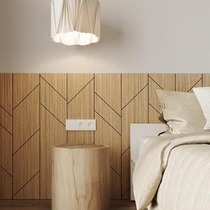 May include: A white, origami-style pendant light hangs above a wooden bedside table with a natural wood finish. The table is next to a bed with a white headboard and beige linen bedding.