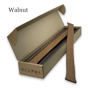 May include: A box of walnut wood veneer strips. The box is open and the strips are visible. The box is labeled with the word "Walnut".