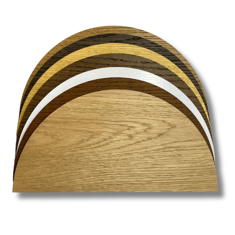 May include: A set of five wooden half-circles, each a different shade of brown, stacked on top of each other. The top half-circle is the darkest brown, and the bottom half-circle is the lightest brown.