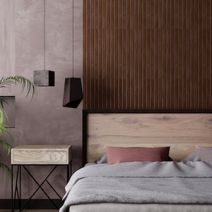 May include: A bedroom with a wooden headboard and a grey duvet. There are two black pendant lights hanging from the ceiling and a wooden bedside table with a drawer.