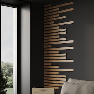 May include: A wall art installation consisting of multiple horizontal wooden slats of varying lengths arranged in a staggered pattern. The slats feature a natural brown wood grain finish and are mounted against a solid dark gray wall surface.