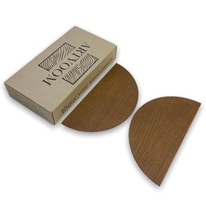 May include: Two half-circle wooden wall panels in a light brown wood grain finish. The panels are packaged in a box with the text "Enjoy your wood panels" and the logo "WOOD ART".