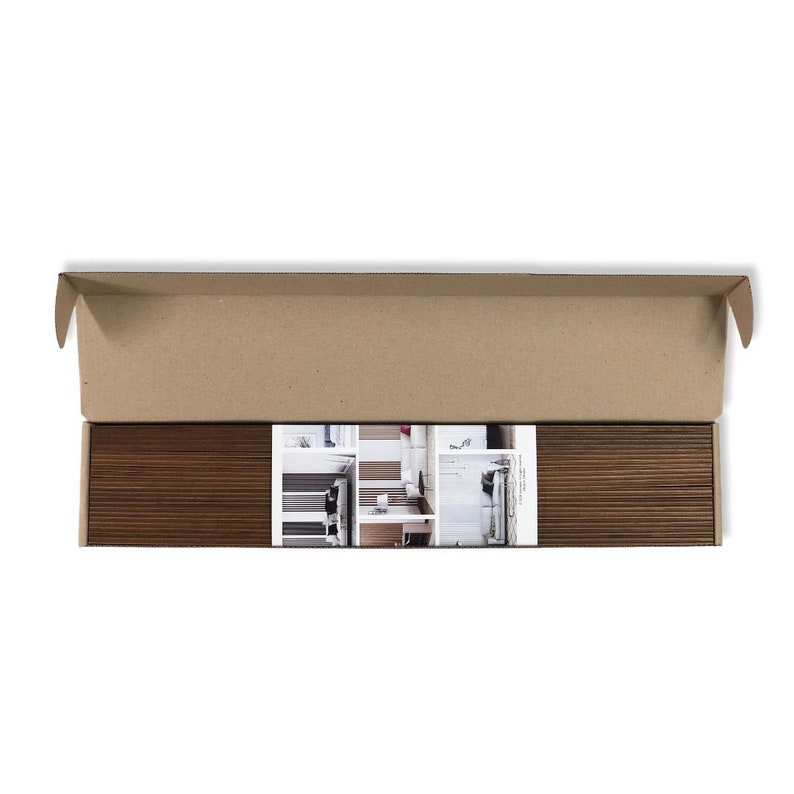 May include: A brown cardboard box is open, revealing a package of wood-look floor tiles. The tiles are arranged in a neat stack and are surrounded by a white paper with a photo of the tiles installed in a room.