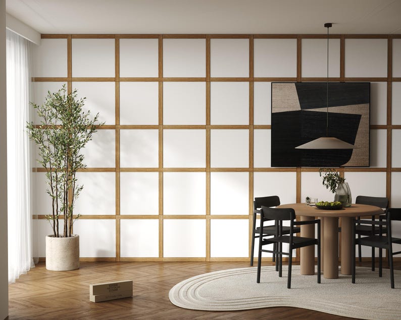 May include: A modern dining room with a wooden table and black chairs. The room features a white wall with a grid pattern and a black and white abstract painting hanging above the table. A potted plant is in the corner of the room.