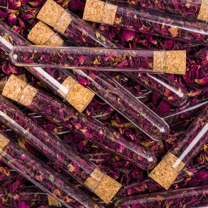 May include: Close-up of a group of glass test tubes filled with dried rose petals. The test tubes have cork stoppers and are arranged in a random pattern.