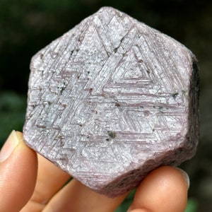 Puede incluir: Un gran cristal de rubí rosa hexagonal con estrías en su superficie.