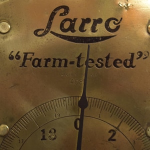 May include: A brass scale with a black needle and a white face. The scale is labeled "Larro" and "Farm-tested".