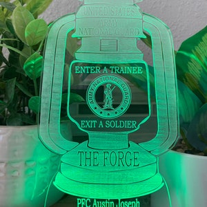 May include: A green illuminated acrylic lantern with the text "United States Army National Guard", "Enter a Trainee", "Exit a Soldier", "The Forge", "PFC Austin Joseph", "Fort Benning", "D2-19", and "2nd Platoon".