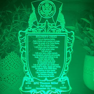 May include: A green illuminated acrylic plaque with the Soldier's Creed, the US Army seal, and the text "SPC Thomas Miller, Fort Moore, December 15, 2024".