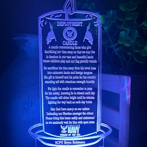 May include: A blue and white candle with a navy theme. The candle has a poem about deployment and a navy seal. The text reads "Deployment Candle, A candle remembering those who give Sacrificing her time away so that we may live in freedom in our vast and beautiful lands where children play and our flag proudly stands He sacrifices his time away from his loved ones into unknown lands and foreign tongues His gift is himself and his pride for his country standing tall with American strength humbly We light the candle to remember to pray for his safety, knowing he is missed each day The candle will shine bright until he returns lighting the way back as each day turns May God have mercy on our sailors Defending our liberties amongst the others Please bring him home safely and unharmed As we anxiously wait for him with open arms America's Navy Forged by the Sea SCPO Bryce Robinson"