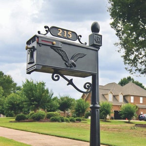 May include: Black mailbox with a gold eagle design and the number 215 on a gold plaque. The mailbox is mounted on a black metal post with a decorative finial.