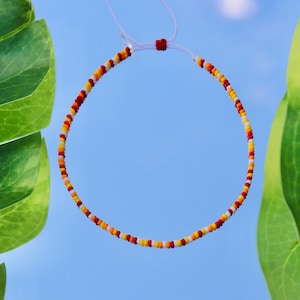 May include: A red, yellow, and white beaded bracelet with a white string closure.