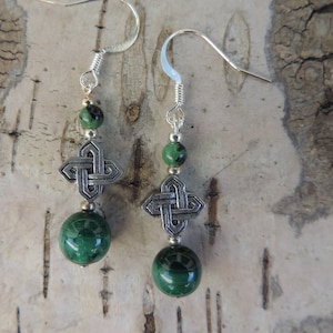 May include: A pair of silver Celtic knot earrings with green malachite beads. The earrings have a simple hook closure.