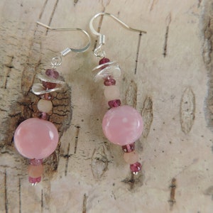 May include: Pink and silver dangle earrings with a large pink round bead, smaller pink beads, and silver spacers.