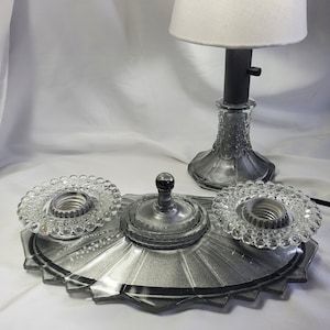 May include: A silver and clear glass three-light ceiling fixture with a decorative, scalloped edge. The fixture has three light sockets with clear glass shades.