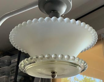 May include: A ceiling light fixture featuring a frosted white glass shade with a scalloped edge of small glass beads. A secondary clear glass ring with larger beads encircles the base, which is finished with a central silver-toned finial.