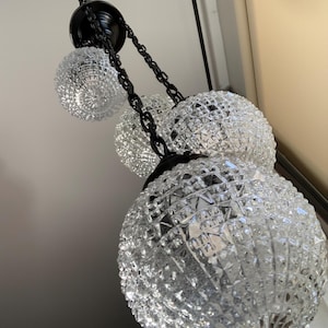 Long waterfall chandelier has a black finish and vintage clear glass light shades. 40 inches long x 11 wide, made of new and antique parts.