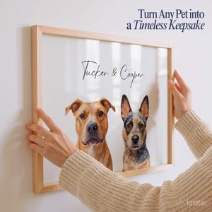 May include: A framed portrait featuring two dogs, a tan Pit Bull mix and a blue heeler, with the names "Tucker & Cooper" in script. The frame is light wood, and the text "Turn Any Pet into a Timeless Keepsake" is at the top.
