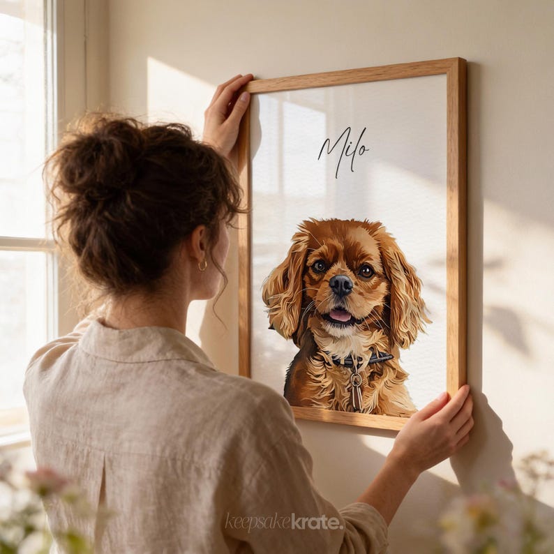 May include: A framed portrait of a Cavalier King Charles Spaniel dog with brown and tan fur. The dog is wearing a collar with a key charm. The name "Milo" is written in cursive at the top of the frame.