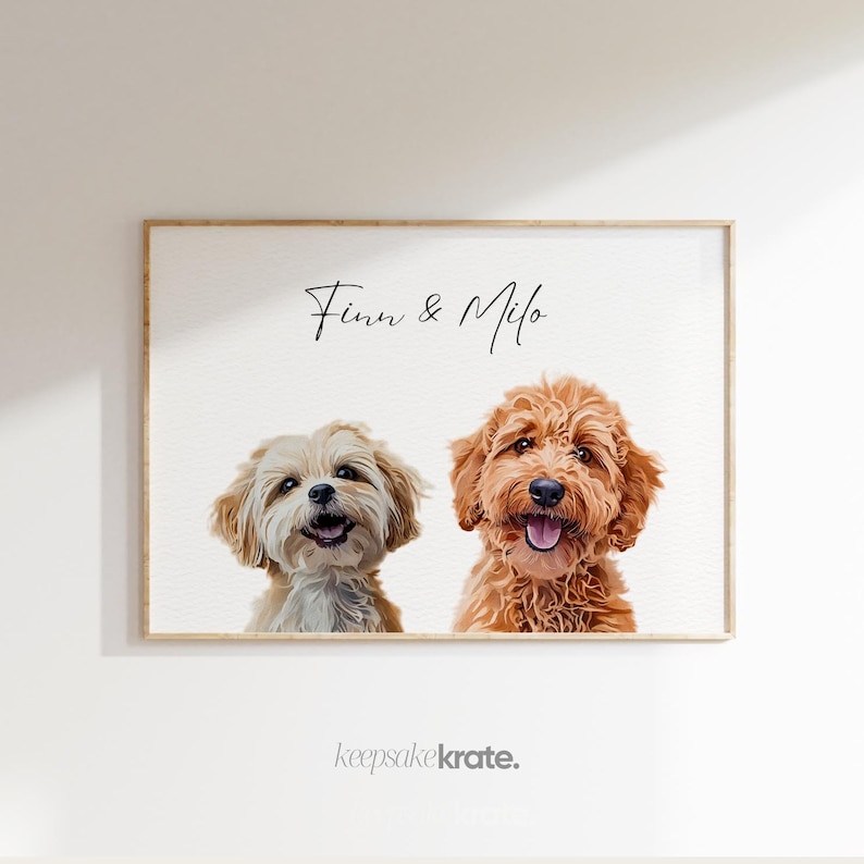 May include: A framed portrait featuring two dogs, a light-colored dog on the left and a reddish-brown dog on the right. The names "Finn & Milo" are written above the dogs. The text "keepsakekrate." is at the bottom.