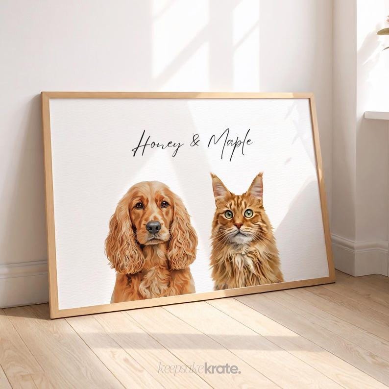 May include: A framed print featuring a golden Cocker Spaniel and a ginger tabby cat. The artwork has the text "Honey & Maple" in script. The print is in a light wood frame, set against a white background.