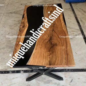 Op de afbeelding: Een rechthoekige houten salontafel met een zwart epoxyhars rivierontwerp. De tafel heeft een natuurlijke houtnerf afwerking en staat op een zwart metalen onderstel. De afmetingen van de tafel zijn niet zichtbaar.