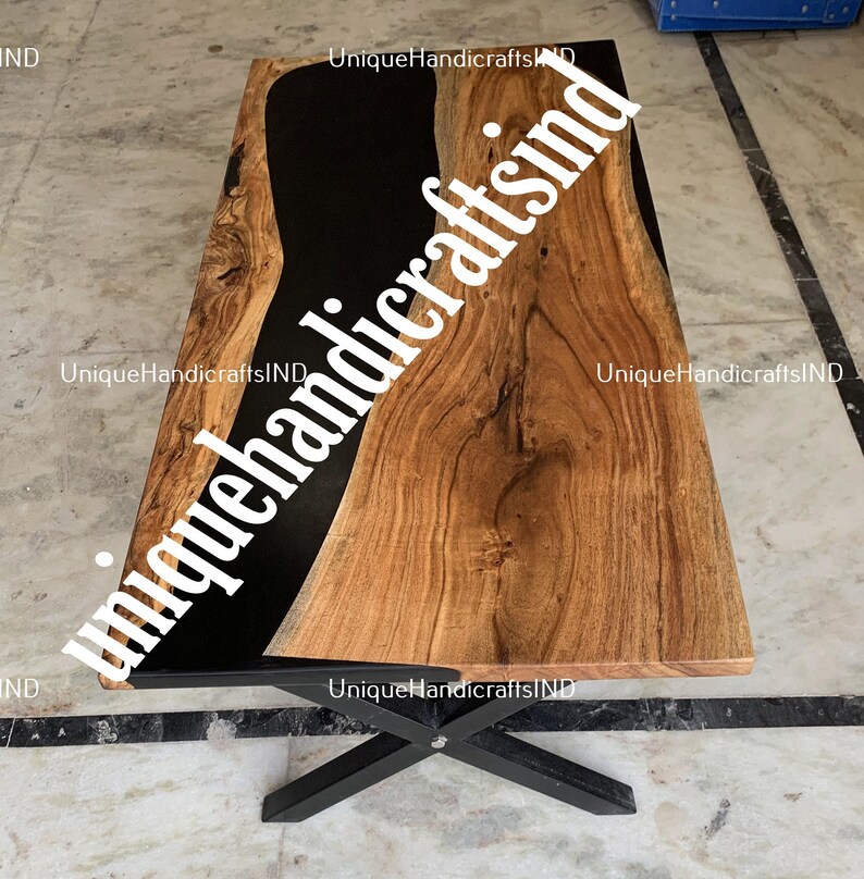 Op de afbeelding: Een rechthoekige houten salontafel met een zwart epoxyhars rivierontwerp. De tafel heeft een natuurlijke houtnerf afwerking en staat op een zwart metalen onderstel. De afmetingen van de tafel zijn niet zichtbaar.