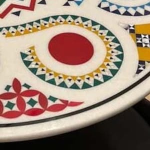 Puede incluir: Una mesa de m&aacute;rmol blanco con un dise&ntilde;o geom&eacute;trico colorido. El dise&ntilde;o presenta un c&iacute;rculo rojo, tri&aacute;ngulos amarillos y verdes y cuadrados negros y blancos.