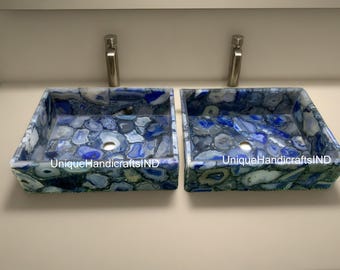 以下が含まれることがあります： ユニークな自然なパターンを持つ、青いアゲートストーン製のベッセルシンクが2つ。各シンクには排水穴が1つあり、「UniqueHandicraftsIND」というラベルが貼られています。