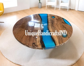 May include: Round wooden coffee table with a blue epoxy resin inlay. The table has a natural wood finish and a unique, flowing design. The text "UniqueHandicraftsIND" is visible on the table.