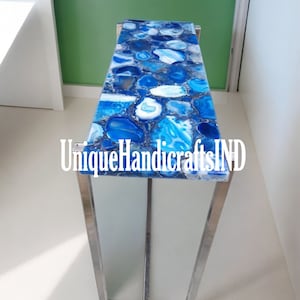 May include: A modern console table with a blue agate stone top and a stainless steel frame. The table is approximately 76 cm long and 30 cm wide.
