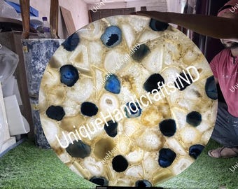 May include: Round agate table top with a white, yellow, and blue agate pattern. The table top is approximately 30 inches in diameter. The text "Unique Handicrafts IND" is visible on the table top.