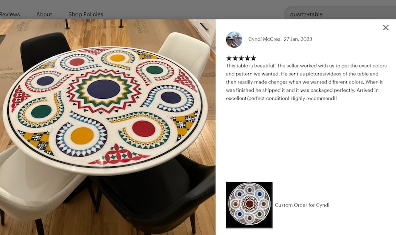 Puede incluir: Una mesa redonda blanca con un dise&ntilde;o geom&eacute;trico colorido. La mesa tiene un patr&oacute;n de cuadros negros y blancos alrededor del borde. La mesa est&aacute; rodeada por cuatro sillas, dos negras y dos blancas.