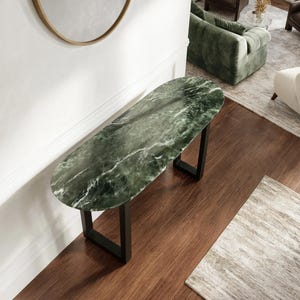 May include: An oval console table featuring a dark green marble top with white veining. The table is supported by two black metal U-shaped legs. The surface of the marble displays natural stone patterns and a polished finish, providing a smooth texture.