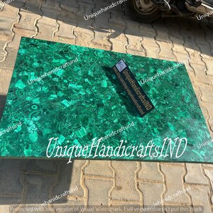 May include: A green malachite table top with a unique pattern. The table top is made of natural stone and has a polished finish. The text "Unique HandicraftsIND" is visible on the table top.
