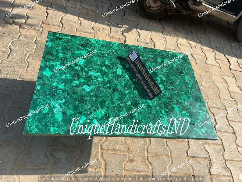 May include: A green malachite table top with a unique pattern. The table top is made of natural stone and has a polished finish. The text "Unique HandicraftsIND" is visible on the table top.
