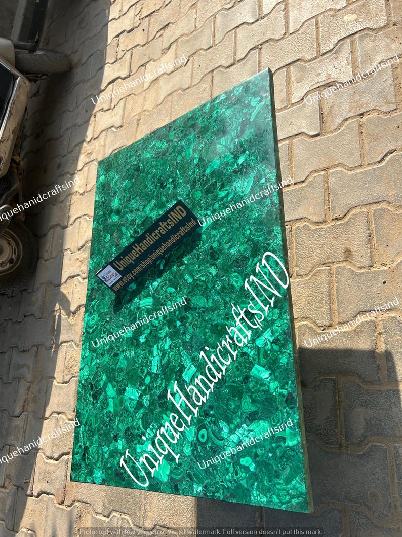 May include: A green malachite table top with a unique pattern. The table top is made of natural stone and has a polished finish. The table top is surrounded by a brick wall.
