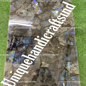 May include: A close-up of a dark blue and black labradorite stone countertop. The stone has a unique, iridescent quality that shimmers in the light. The countertop is ideal for a kitchen or bathroom.