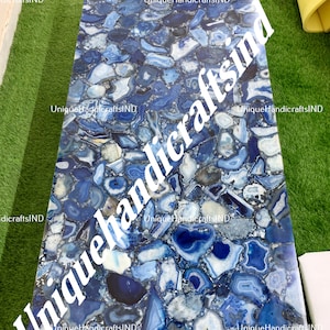 Könnte beinhalten: Blaue Achat-Tischplatte mit einem einzigartigen Muster aus blauen und weißen Achat-Scheiben. Die Tischplatte ist aus Naturstein gefertigt und hat eine polierte Oberfläche.