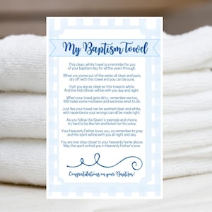 May include: A stack of white bath towels next to a baptism card. The card has a blue and white border and text that reads "My Baptism Towel" and "Congratulations on your Baptism!"